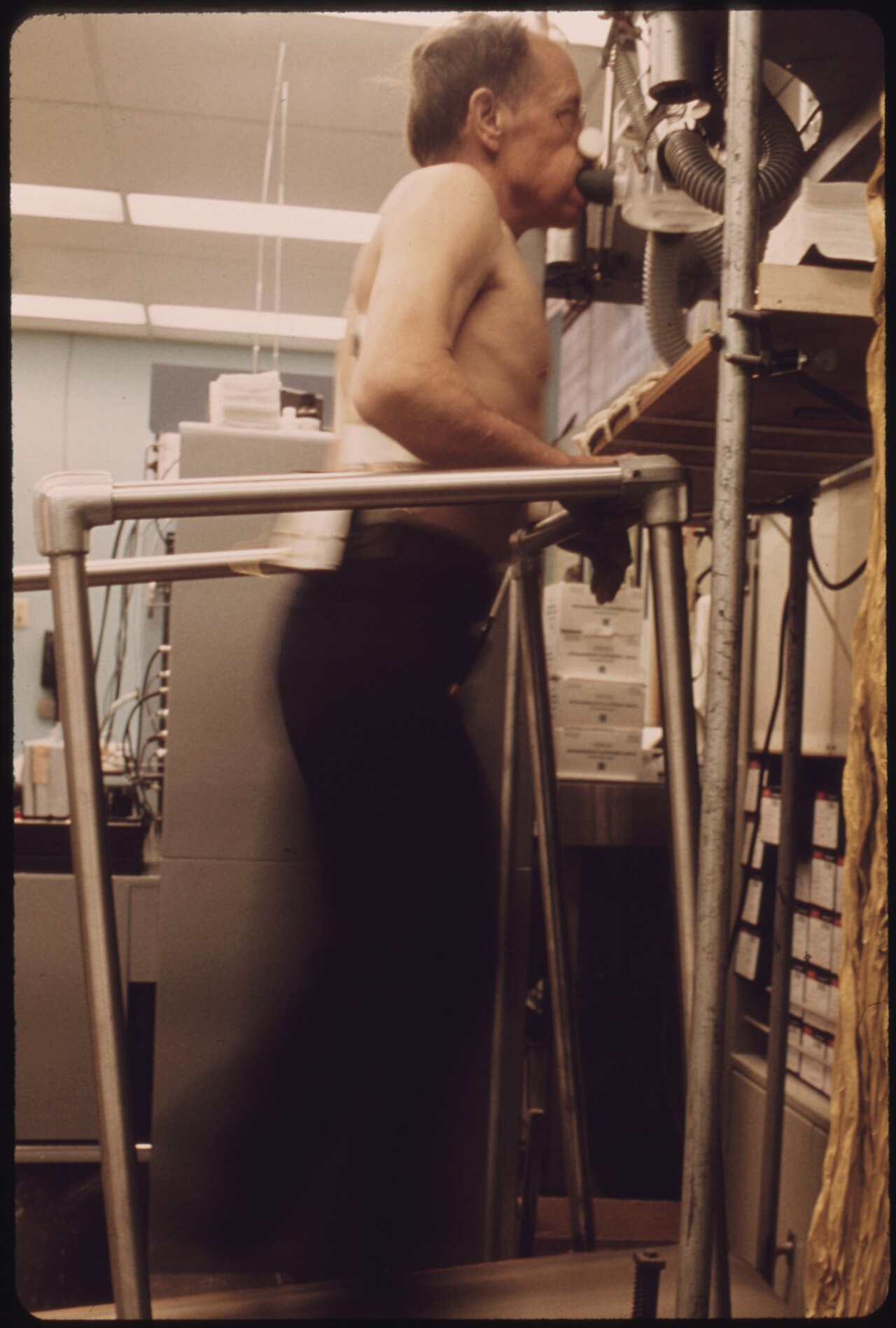 MINER IS HOOKED UP TO A BREATH MACHINE TO MONITOR HOW MUCH LUNG CAPACITY HE HAS WHILE WALKING ON A TREADMILL DURING... - NARA - 556569.jpg